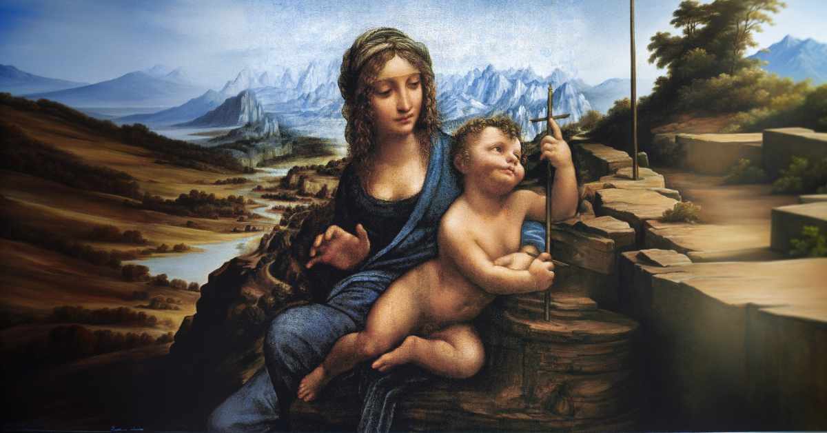 This image features a painting of a woman holding a child on her lap, rendered in a style reminiscent of Renaissance art. The woman, dressed in a flowing blue robe, gently supports the child with her left arm and hand. The child, nude except for a subtle blue sash, looks upward while grasping a tall thin cross. Both figures are depicted with soft, idealized features typical of classical artworks. The background presents a panoramic landscape, consisting of a river valley leading towards distant, jagged mountains. The valley is marked by patches of forests and fields in varying shades of brown and green. To the right, the terrain transitions into rocky cliffs and winding paths, indicating a rugged terrain. The overall composition and color palette give the painting a serene and timeless quality.