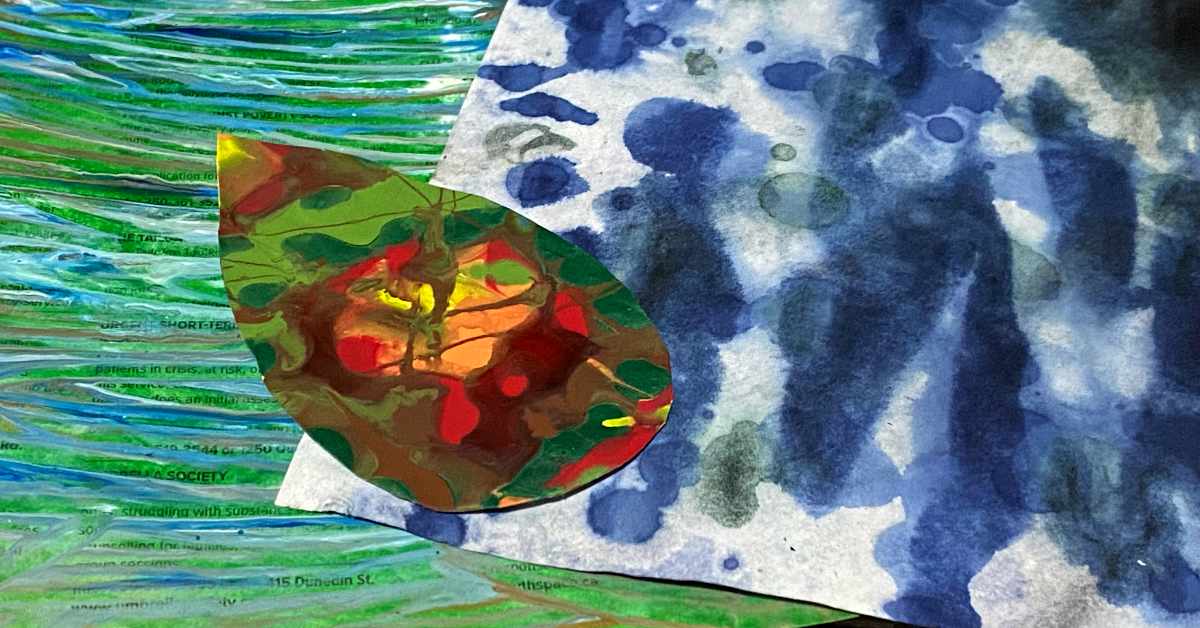 A pile of mixed media components featuring a cut-out paper shape resembling a leaf, painted in vibrant red, green, yellow, and brown swirls. The leaf is placed on top of a blue and white dyed background with a loose marbled pattern, which overlaps a green, text-printed surface resembling a page with wavy blue, green gold and white lines. The composition combines abstract painting, collage, and text elements.